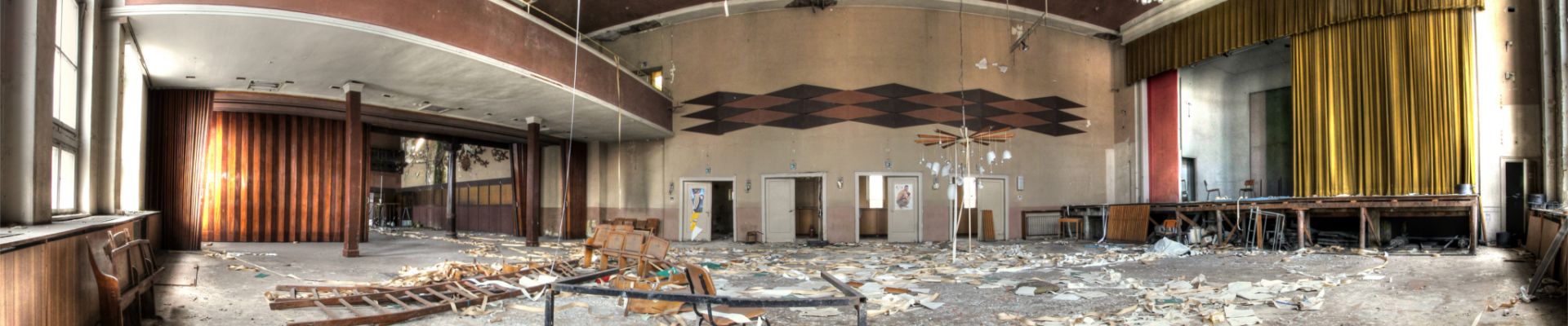 Verlassener Saal mit Bühne und Balkon.